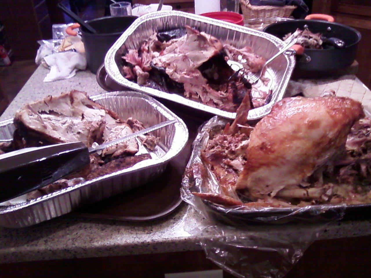Three cooked and partially eaten turkeys in separate roasting pans